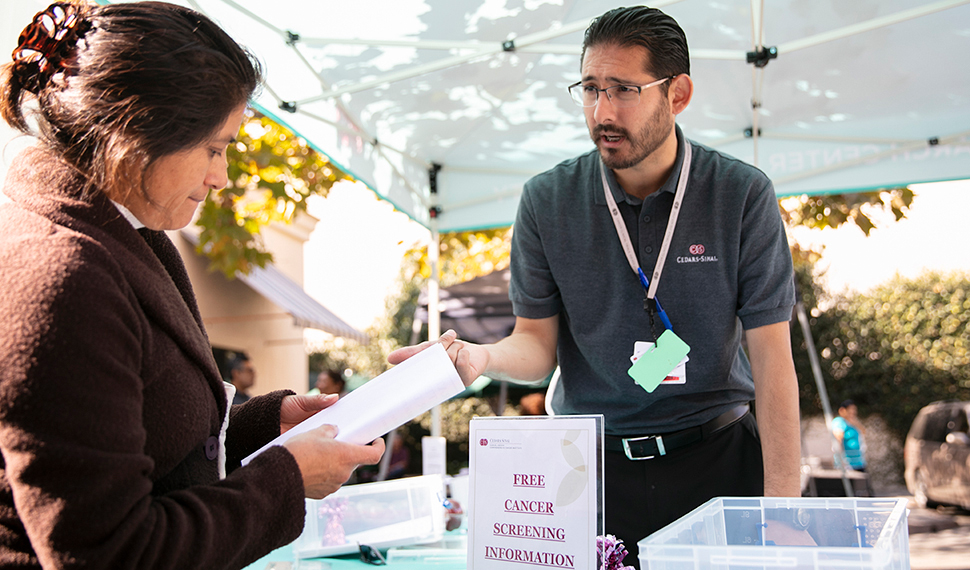 Ergueen Herrera, community outreach coordinator at the Cancer Research Center for Health Equity, setting up an information booth at the St. Thomas the Apostle church to provide navigation to free local cancer screening resources in the Pico/Union neighborhood of Los Angeles. (2018)