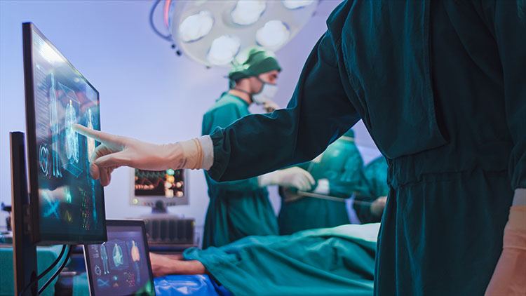 Doctor pointing on a computer monitor during a surgical procedure