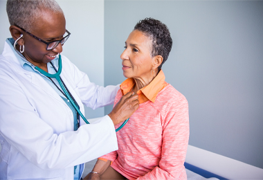 Senior female doctor examining smiling patient in hospital