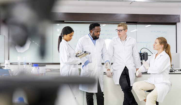 Group of Scientists working in laboratory having discussion on testing data together.