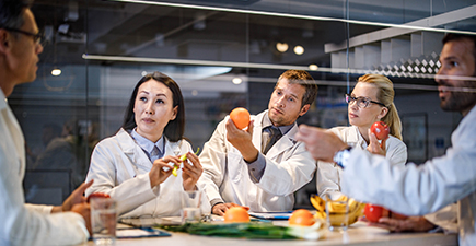 Group of medical experts holding variation of fruit and vegetables during a meeting in the office. 