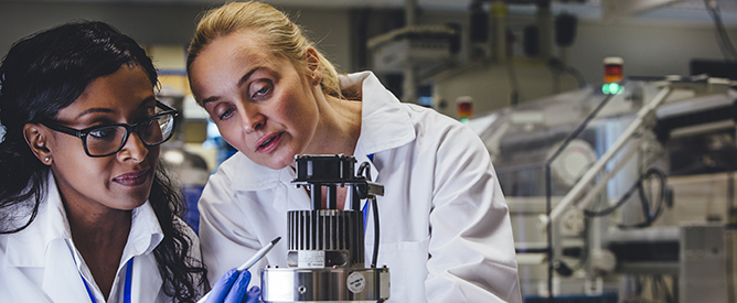 Two female medical engineers examining a piece of equipment.