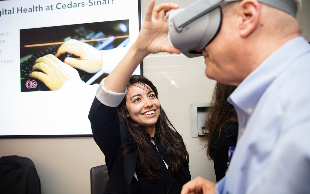 aura Garcia helps Robert Chernoff, PhD, adjust his VR goggles at the 2019 Cedars-Sinai Virtual Medicine Conference